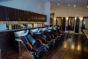 Interior of a hair and makeup salon with empty chairs and product shelves. - Hollywood Hair Salon and Spa in Centralia, IL