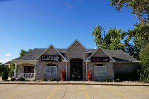 Single-story brick commercial building with a gabled entrance and a sign reading "Mallory Funeral Home," featuring makeup services. - Hollywood Hair Salon and Spa in Centralia, IL