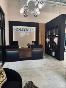 Reception area of Edwardsville’s "Hollywood Hair" salon, featuring two desks with computers, a flower arrangement, and a shelving unit displaying products. - Hollywood Hair Salon and Spa in Centralia, IL